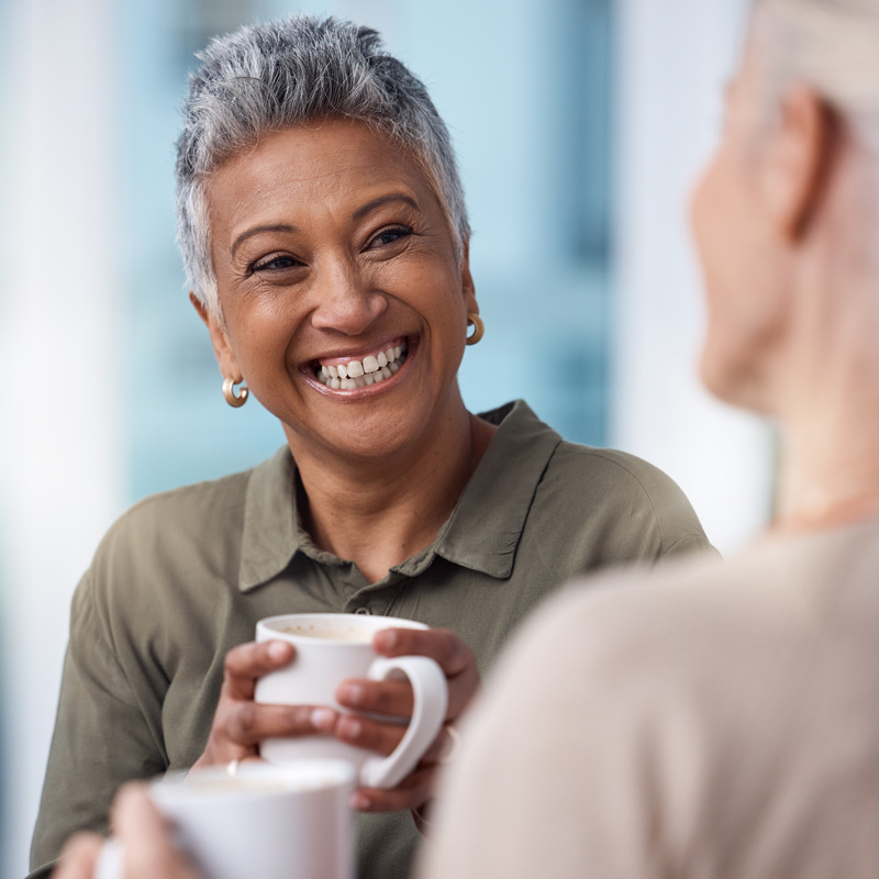 A lady sipping coffee and chatting with a friend in Houston, TX